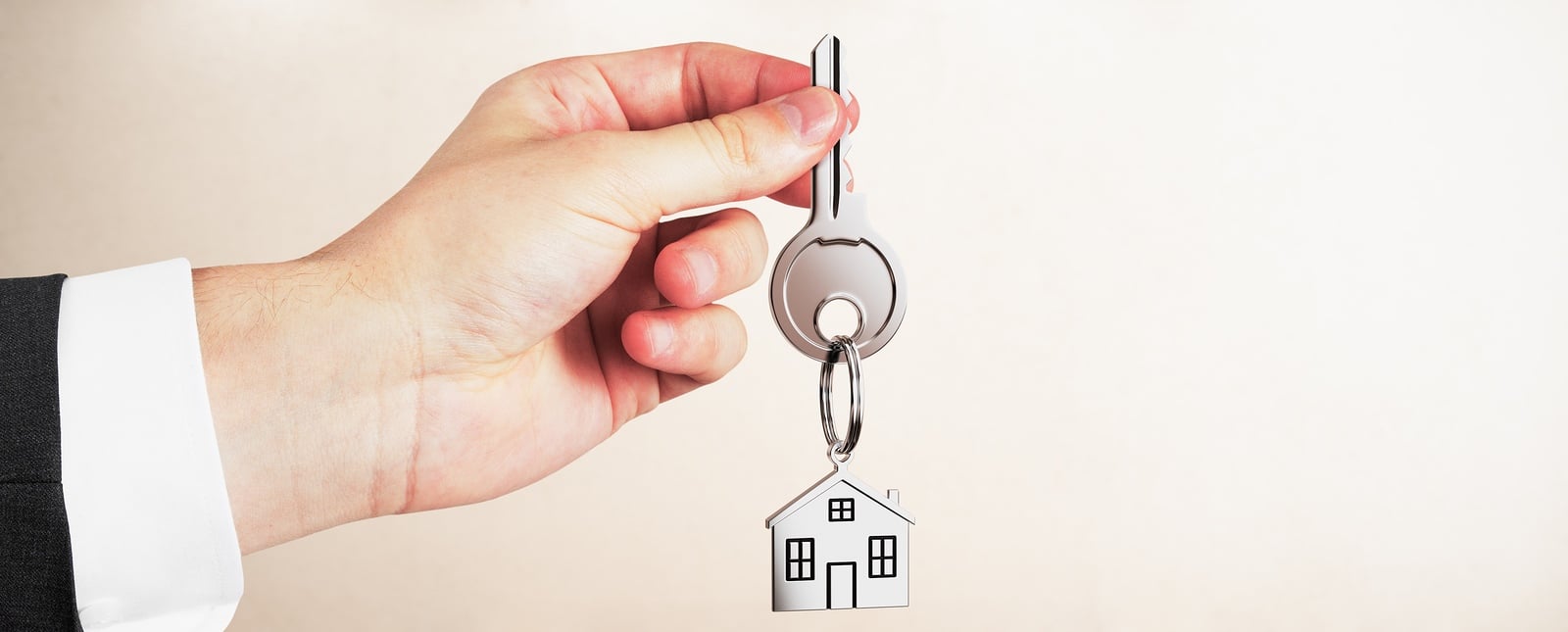 Real estate agent holding keys on light empty interior background