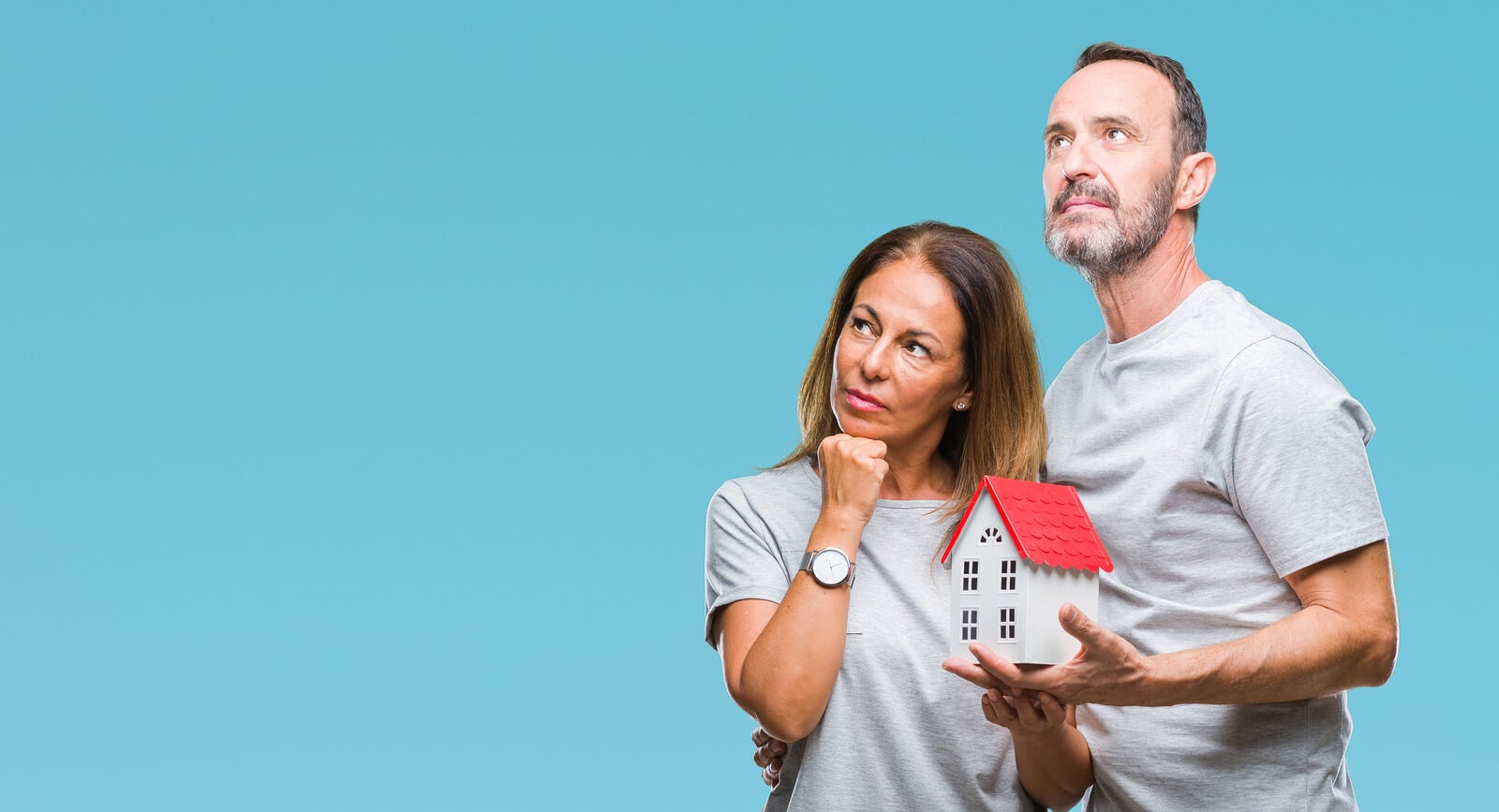 a couple holding a house and looking thoughtful