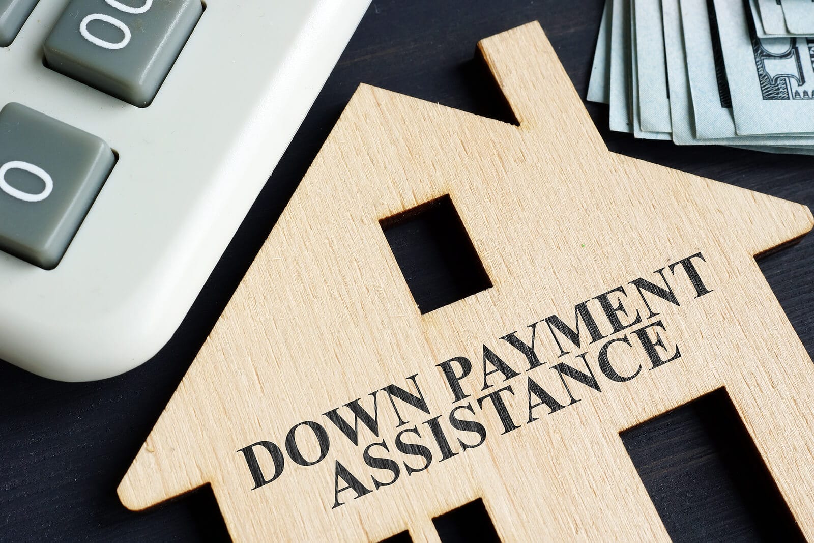 the words down payment assistance etched into a cut out of a house