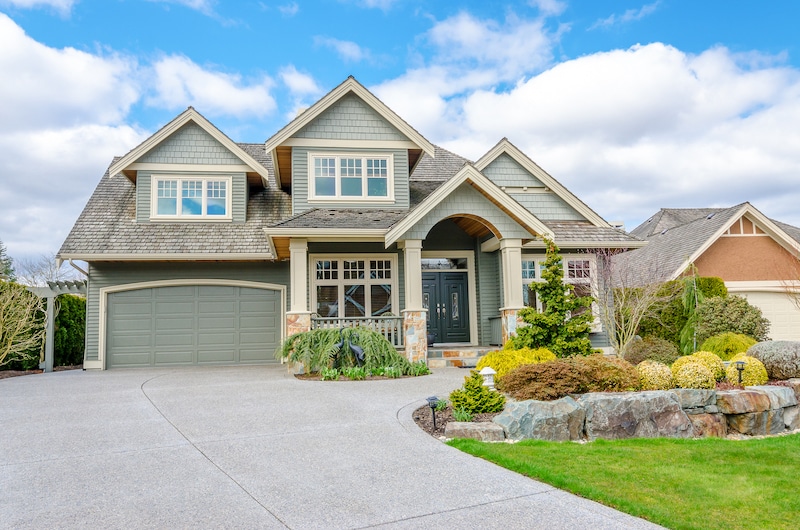 Luxury house with a two-car garage and beautiful landscaping on a sunny day. Home exterior.